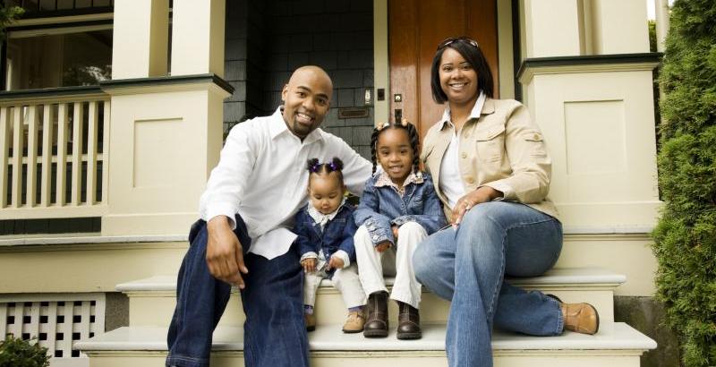 a family of four sitting on the steps on their home