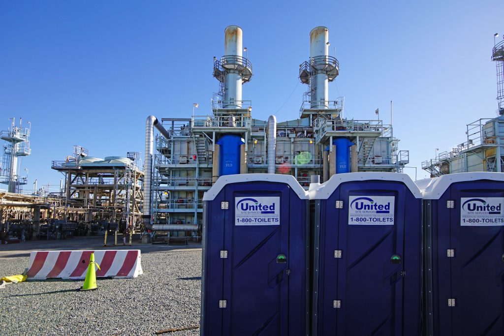 three blue porta potties at an industrial facility