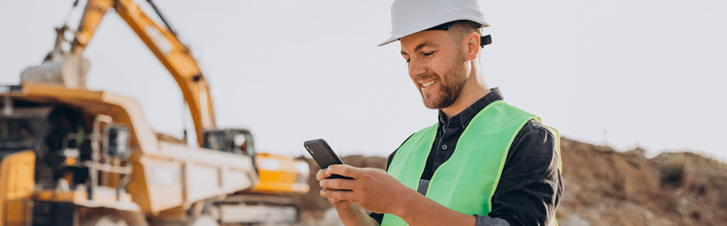 a construction worker on a job site looking at his mobile phone