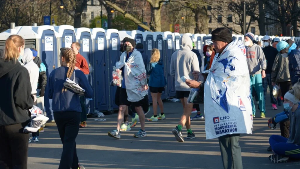 marathon participants walking around after the race in front of a row of porta potties